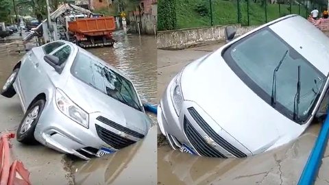 Carro cai em buraco e fica submerso em rua alagada após chuva - Imagem: Reprodução/O São Gonçalo