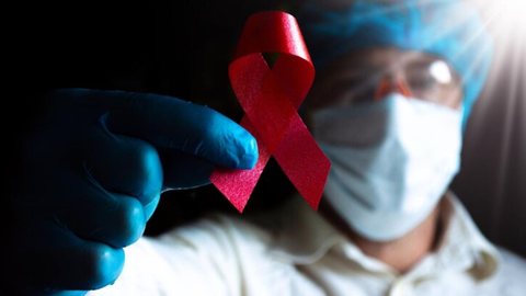Profissional de saúde segura placa em apoio à luta contra a AIDS - Imagem: Reprodução / Freepik