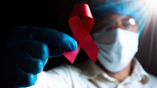 Profissional de saúde segura placa em apoio à luta contra a AIDS - Imagem: Reprodução / Freepik