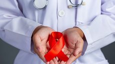 Médico segura laço vermelho em campanha de conscientização sobre HIV/Aids - Imagem: Reprodução / Freepik