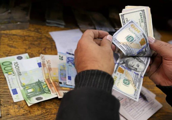 Homem conta notas de dólar e euro. - Foto: Reuters