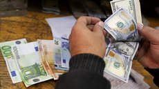 Homem conta notas de dólar e euro. - Foto: Reuters