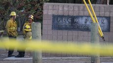 Imagem: Ringo H.W. Chiu/AP - Bombeiros permanecem ao lado de fachada do parque Peck Park, em Los Angeles (EUA)