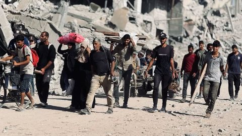 Moradores de Khan Younis percorrem os escombros de suas casas, carregando os poucos pertences que restaram após os bombardeios - Imagem: Reprodução / X / @Timesofgaza
