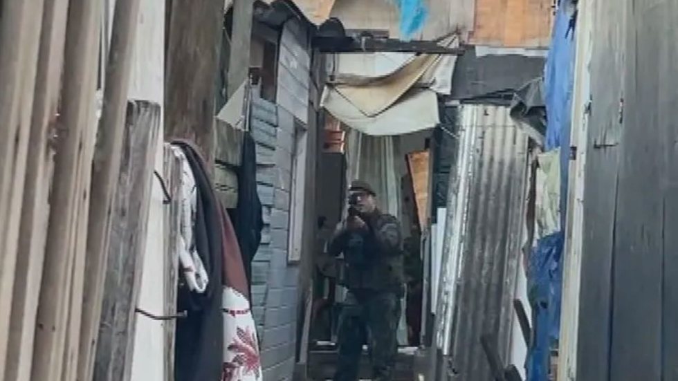 VÍDEO - Policial Militar aponta fuzil para repórter durante matéria em comunidade - Imagem: reprodução TV Globo