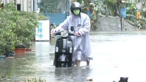 Homem com uma scooter atravessa a água da enchente causada pela passagem do tufão Mekkhala em Taiwan - Imagem: Reprodução/CTS via REUTERS TV