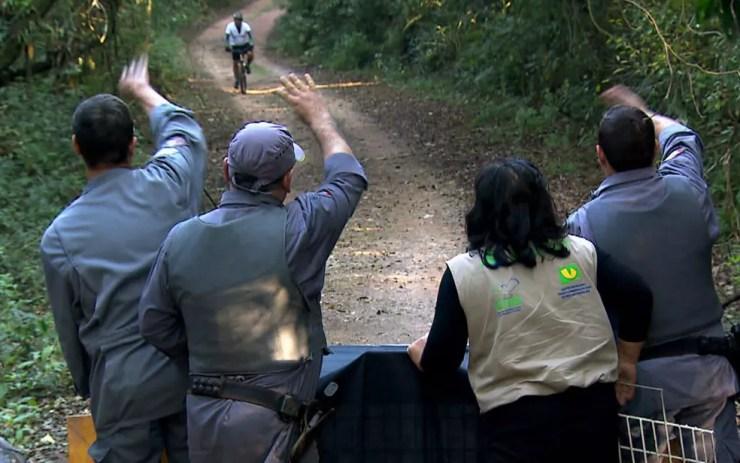 Bombeiros e funcionários de ONG avisa ciclista que onça será libertada na trilha em Cotia (Foto: TV Globo/Reprodução)