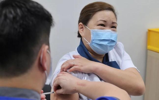  A enfermeira Sarah Lim, de 46 anos, recebe a primeira vacina contra o coronavírus aplicada em Singapura, no Centro Nacional de Doenças Infecciosas, na quarta-feira (30) — Foto: Lee Jia Wen/Ministry of Communications and Information/Handout via Reuters
