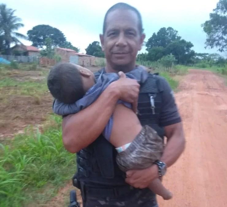 Policial Adilson de Figueiredo, do GOE, segura uma das crianças que foi resgatada em Nova Lacerda — Foto: Gerência de Operações Especiais (GOE)