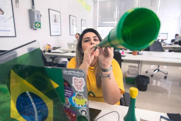 A analista de SEO da GetNinjas Mariana da Silva Cremonesi enfeitou a sua mesa quase um mês antes da Copa; empresa vai liberar funcionários para ver os jogos (Foto: Marcelo Brandt/G1)