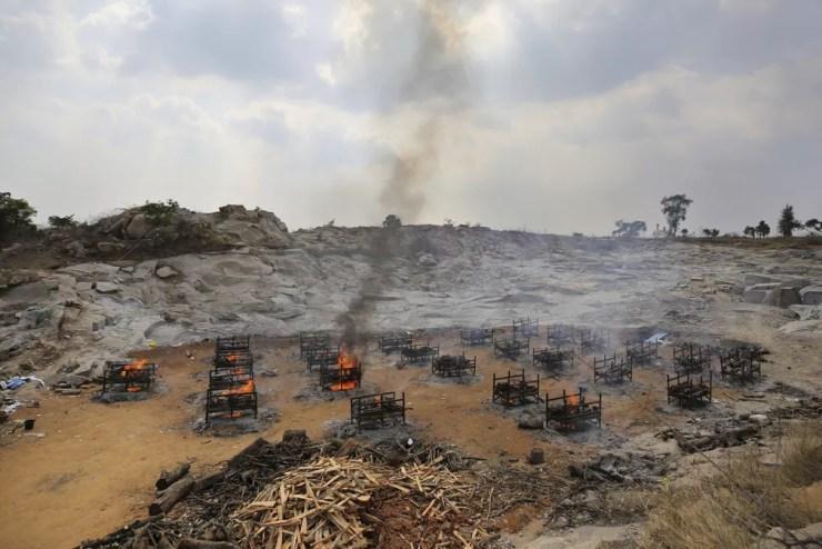 Piras funerárias de 25 vítimas da Covid-19 queimam em crematório a céu aberto criado em uma pedreira de granito nos arredores de Bengaluru, na Índia, em 5 de maio de 2021 — Foto: Aijaz Rahi/AP