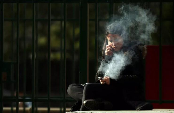 Jovem fuma cigarro eletrônico enquanto fala ao celular em Buenos Aires; público jovem é o mais vulnerável aos atrativos do dispositivo  (Foto: REUTERS/Marcos Brindicci)