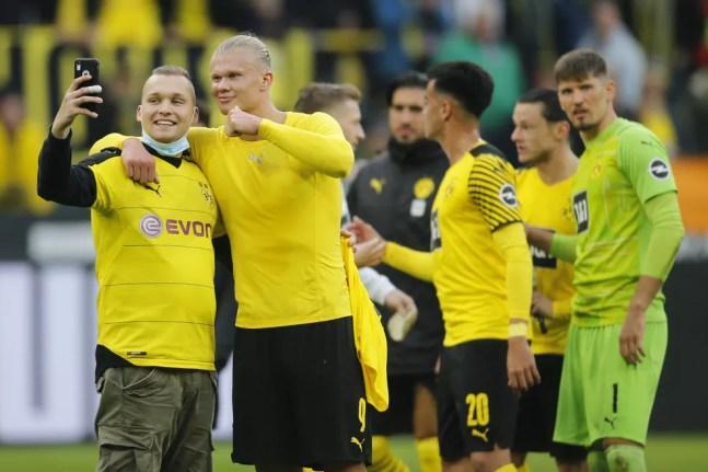 Haaland tira foto com fã em campo na comemoração da vitória do Borussia Dortmund — Foto: REUTERS/Leon Kuegeler 
