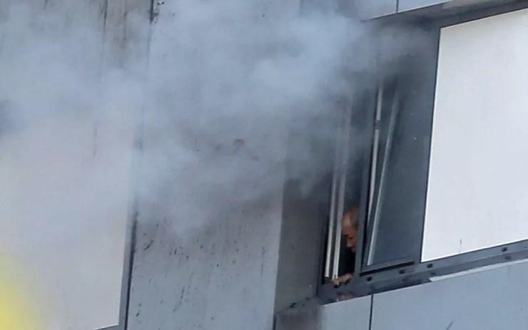 Um homem preso da Grenfell Tower olha para fora enquanto fumaça sai pela janela (Foto: Daniel Leal-Olivas / AFP Photo)