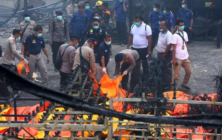 Policiais indonésios carregam corpos das vítimas de explosão de fábrica de fogos de artifício em Tangerang (Foto: Antara Foto/Muhammad Iqbal via Reuters)