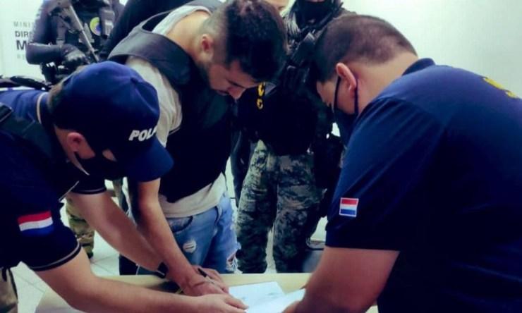 Traficante assina documentos antes de ser entregue às autoridades brasileiras em Foz do Iguaçu Foto: Divulgação