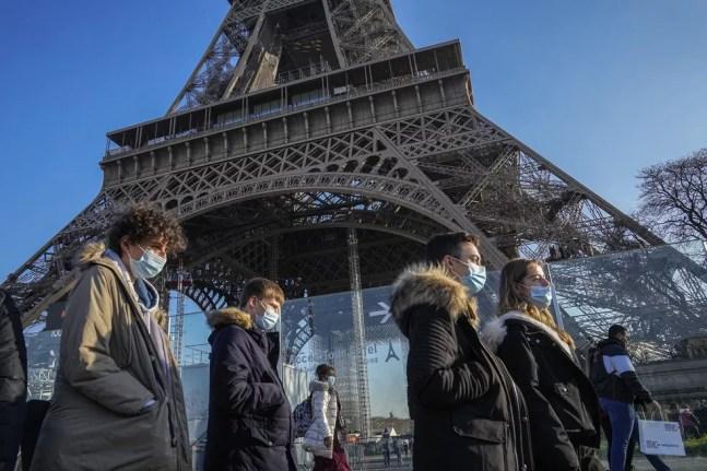 Jovens com máscaras para se proteger da Covid-19 caminham em frente à Torre Eiffel, em Paris, na França, em 21 de dezembro de 2021 — Foto: Michel Euler/AP