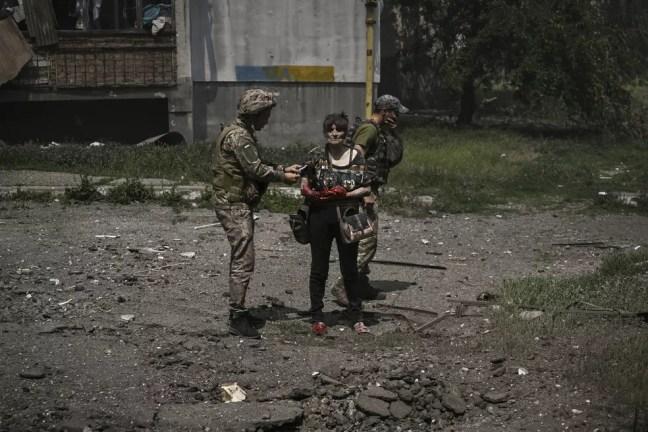 Mulher ferida após batalha entre tropas da Ucrânia e da Rússia é atendida por soldado ucraniano em Lysychansk, no leste do país, em 13 de junho de 2022. — Foto: Aris Messinis/ AFP