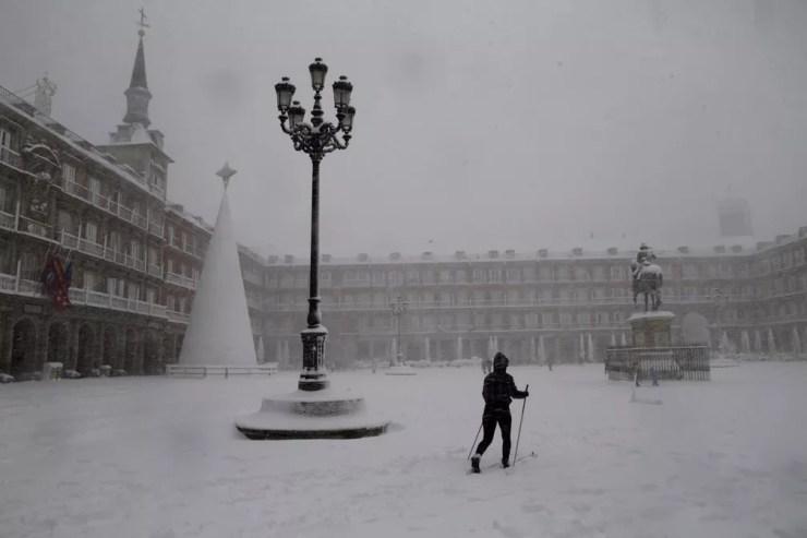 Uma mulher esquia ao cruzar a Plaza Mayor em Madrid durante uma forte nevasca — Foto: Andrea Comas/AP Photo