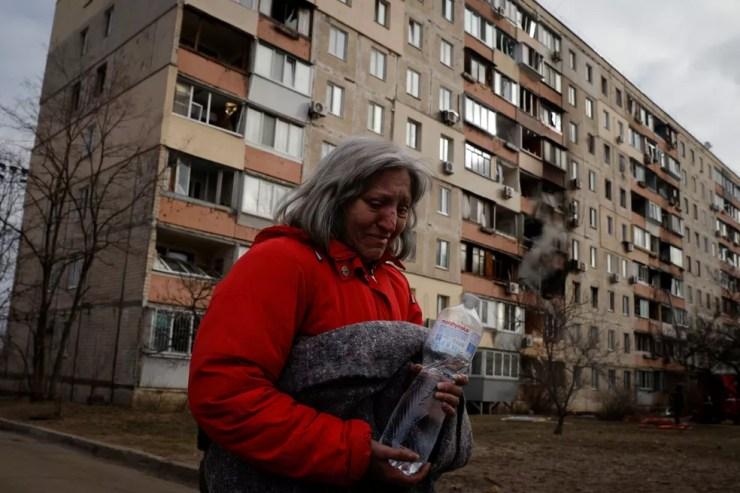 Mulher sai com seu gato de prédio que foi atacado em Kiev, em 14 de março de 2022 — Foto: Thomas Peter/Reuters