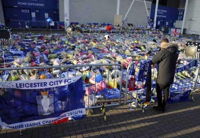 Uma pessoa presta homenagem às vítimas do acidente de helicóptero, que matou o presidente do Leicester City. — Foto: Rui Vieira/Associated Press