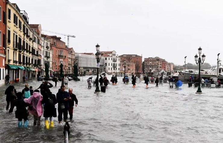Pessoas caminham em Veneza após inundação atingir nível recorde na segunda-feira (29). Inundação foi causada pela convergência da maré alta e de fortes ventos — Foto: Miguel Medina / AFP