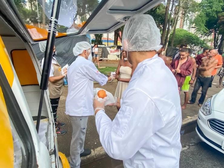 Cristóvam e William distribuem o pão que já comeram nas ruas — Foto: Celso Tavares/g1