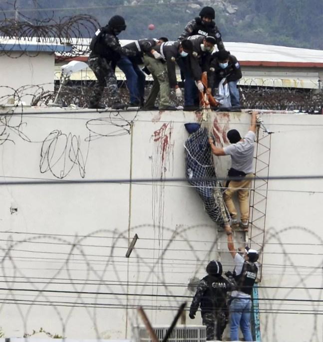 Agentes resgatam um corpo do teto da penitenciária onde houve uma rebelião em Guayaquil, em 13 de novembro de 2021 — Foto: Jose Sanchez/AP