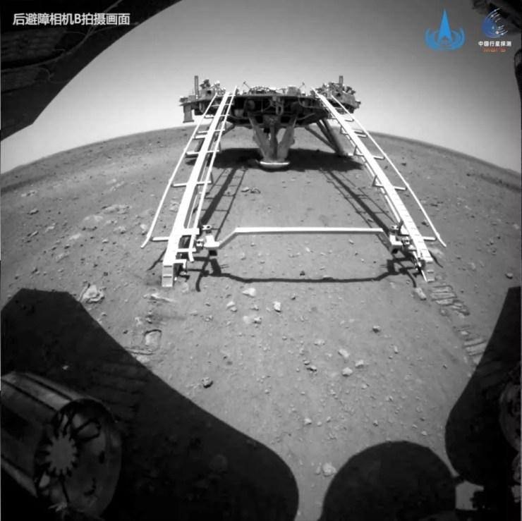Foto mostra robô Zhurong descendo da plataforma de pouso (com os trilhos brancos) e tocando pela primeira vez o solo de Marte, neste sábado (22), em imagem divulgada pela Administração Nacional Espacial Chinesa. — Foto: CNSA/Handout via Reuters