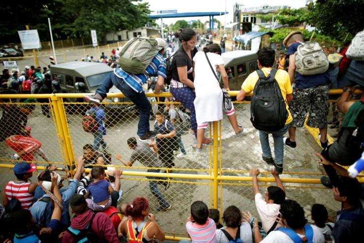 Imigrantes pulam grade na fronteira da Guatemala com o México nesta sexta-feira (19); caravana com milhares de imigrantes atravessa rumo aos EUA — Foto: Ueslei Marcelino/Reuters