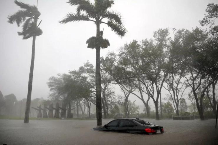 Carro parcialmente submerso é visto em uma área inundada de Coconut Grove, em Miami, na Flórida (Foto: Carlos Barria/Reuters)