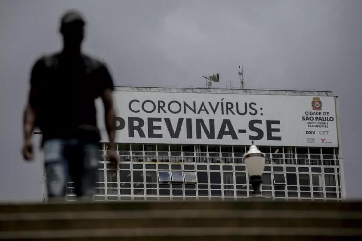 Pedestre passa por cartaz que pede prevenção contra o coronavírus, no Centro de São Paulo. — Foto: Suamy Beydoun/Estadão Conteúdo