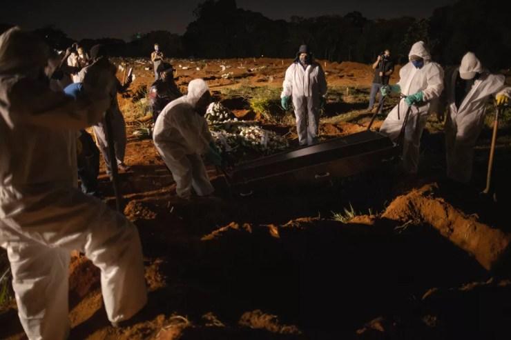 Coveiros usando equipamento de proteção são vistos trabalhando em sepultamento noturno no cemitério da Vila Formosa, Zona Leste da cidade de São Paulo, nesta sexta-feira (26) — Foto: ETTORE CHIEREGUINI/ESTADÃO CONTEÚDO