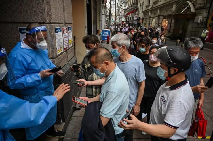 Trabalhadores de um shopping da cidade mostram exames de Covid-19 para poder entrar no local, em 31 de maio de 2022.  — Foto: Hector Retamal/ AFP