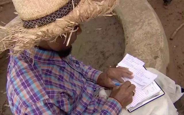 Marcos Reis escreve currículos à mão para entregar em Senador Canedo, Goiás — Foto: Reprodução/TV Anhanguera