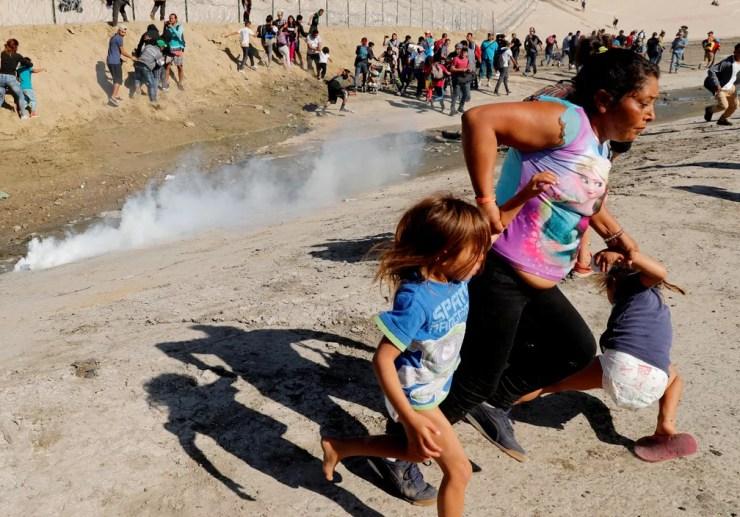 Hondurenha foge com filhas de gás lacrimogêneo lançado na fronteira do México com os EUA — Foto: Kim Kyung-Hoon/Reuters