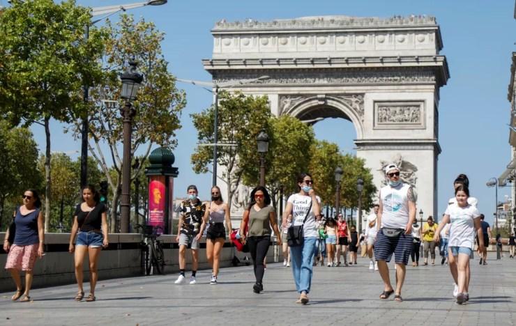Pessoas caminham na Champs-Elysees, perto do Arco do Triunfo, em Paris, nesta quarta-feira (12), enquanto a França reforça o uso de máscara como parte dos esforços para conter o ressurgimento da Covid-19 no país — Foto: Charles Platiau/Reuters