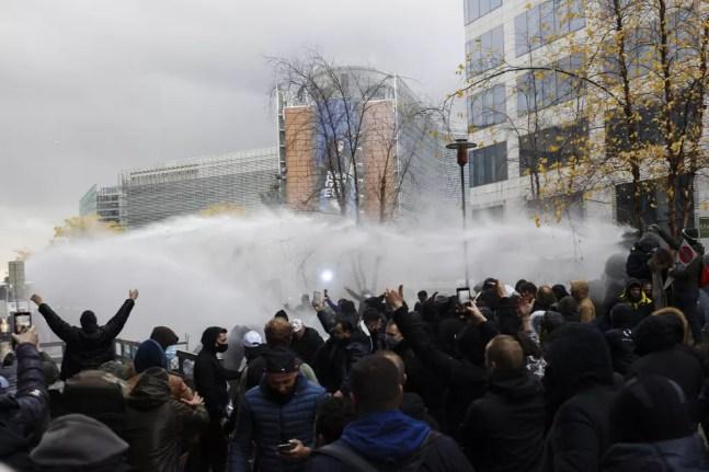 Polícia usa canhão de água contra os manifestantes durante protesto neste domingo em Bruxelas, na Bélgica. — Foto: Olivier Matthys/AP Photo