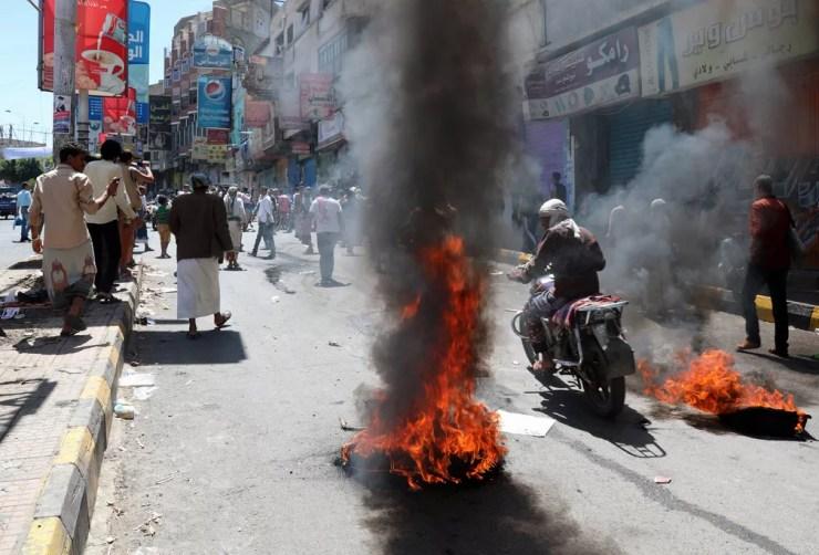 Pneus em chamas são vistos durante um protesto contra a inflação e o custo de vida em Taez, no Iêmen. Um alerta da ONU em setembro mostrou que a desvalorização da moeda pode levar 3.5 milhões de pessoas à fome no país, onde já estão 8.4 milhões  — Foto: Ahmad Al-Basha/AFP
