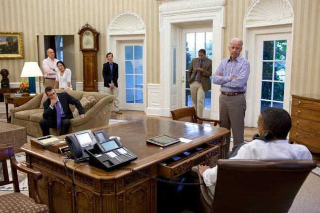 Joe Biden (à direita, em pé) com Barack Obama (à direita, sentado de costas) e outros membros de seu gabinete em 2011, durante negociação do teto de dívida dos EUA — Foto: Reprodução/Imprensa da Casa Branca