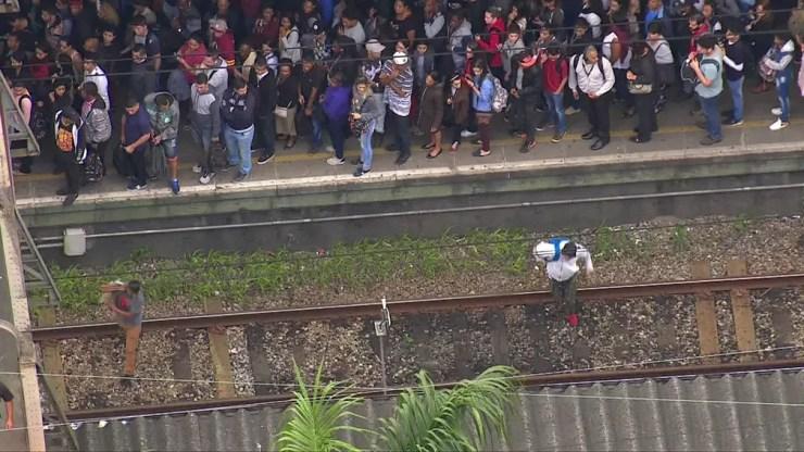 Passageiros atravessam passarela pela linha de trem da CPTM após falha na linha 7 — Foto: Reprodução TV Globo