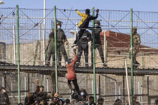Observados por policiais espanhóis, migrantes escalam cerca que separa Marrocos de Melilla, cidade espanhola no norte da África, em 24 de junho de 2022. — Foto: Javier Bernardo/ Associated Press