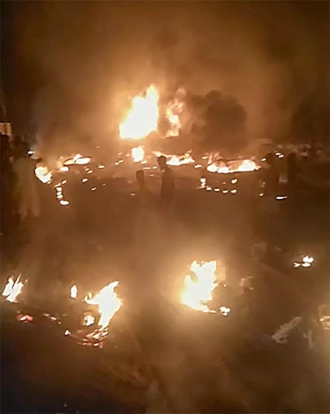 Nesta imagem, feita a partir de vídeo, pessoas caminham por destroços em chamas após a explosão de um petroleiro no subúrbio de Wellington, na capital de Serra Leoa, Freetown, na sexta-feira (5). A explosão que matou dezenas de pessoas ocorreu depois que um ônibus atingiu o petroleiro. (Foto AP) — Foto: AP