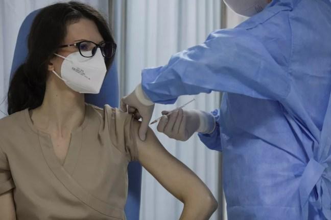 Uma enfermeira romena recebe a injeção da vacina contra a Covid-19 em Bucareste, em 27 de dezembro de 2020 — Foto: Octav Ganea/Reuters