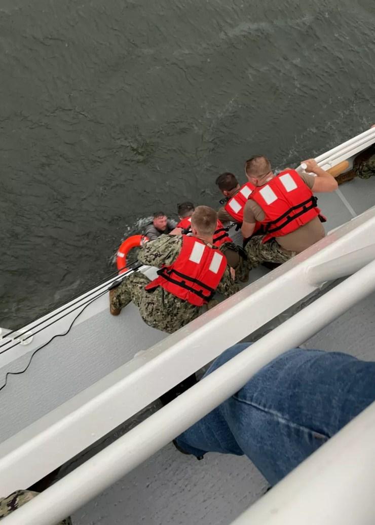 Membros da guarda costeira dos EUA puxam uma pessoa da água, em 13 de abril de 2021 — Foto: Divulgação/Guarda Costeira dos EUA/Via Reuters