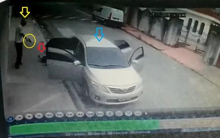 Em outra foto a partir da imagem da câmera de segurança, PM (marcações em amarelo) observa criminoso baleado (marcação vermelha) após tentar roubá-lo durante corrida de Uber com seu carro (azul). — Foto: Reprodução/Montagem/Inquérito policial