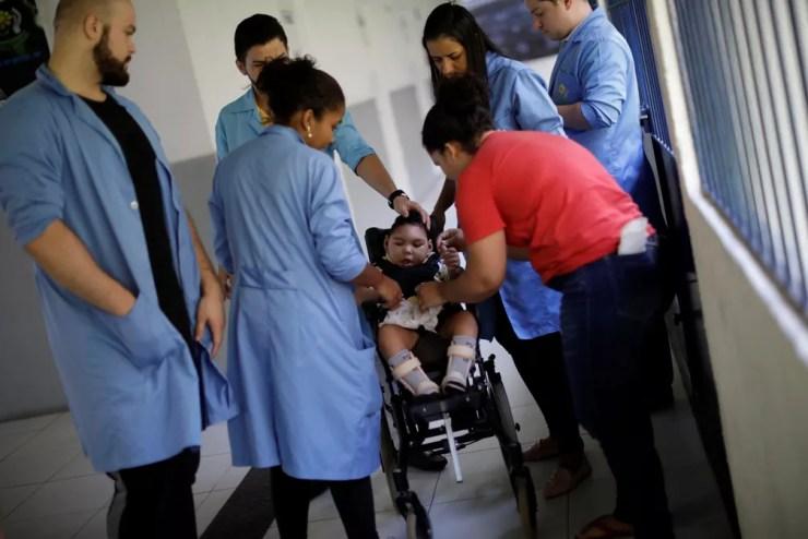 Jackeline Vieira de Souza (de vermelho), 28, mãe de Daniel Vieira, que tem dois anos de idade e nasceu com microcefalia, durante uma sessão de fisioterapia na APAE, no Recife — Foto: Ueslei Marcelino/Reuters