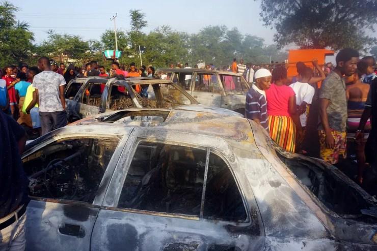 Pessoas observam carros queimados na manhã de sábado (6) após a explosão, na sexta-feira (5), de um tanque de combustível em Freetown, capital de Serra Leoa. — Foto: Saidu Bah / AFP