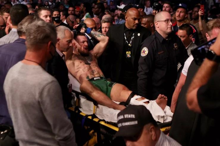 Para Khabib, Conor McGregor (saindo de maca do octógono) jamais será o mesmo após lesão na perna — Foto: Getty Images