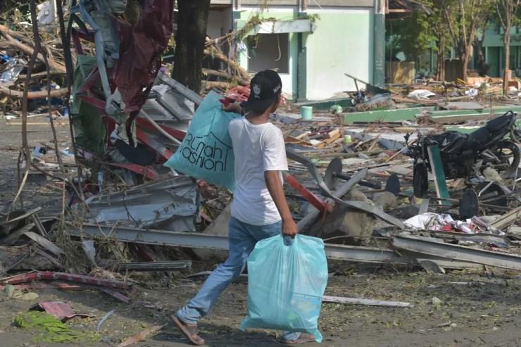 Um homem carrega sacos com itens de uma loja em Palu, na Indonésia, após o terremoto e tsunami neste sábado (30) — Foto: Adek Berry/AFP
